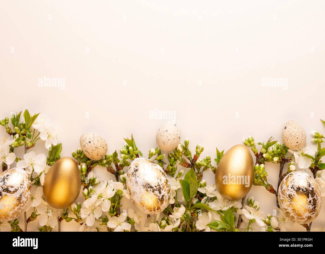 Gold and speckled eggs are arranged on a simple surface with white flowers and green leaves. This setup is for a spring celebration or Easter decorati Stock Photo