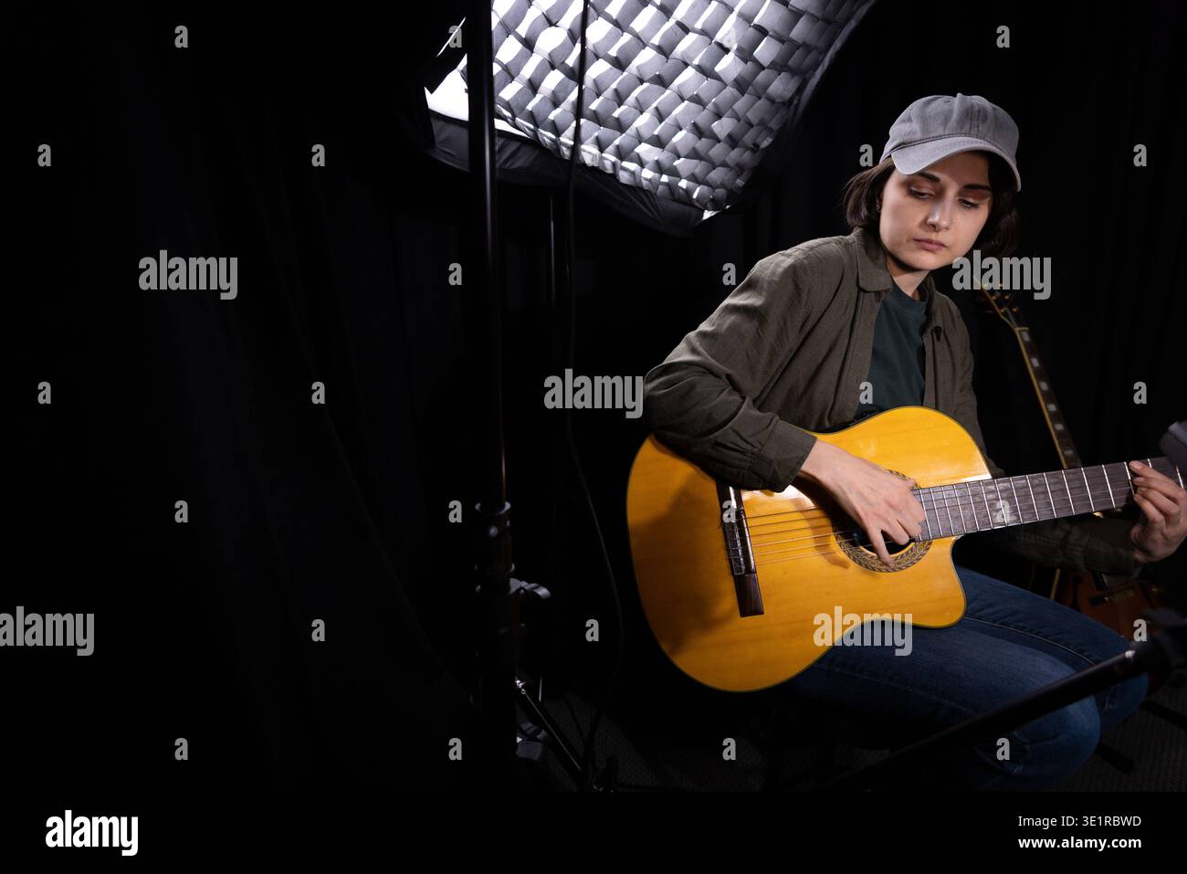 Female Artist Playing Acoustic Guitar in Studio Stock Photo