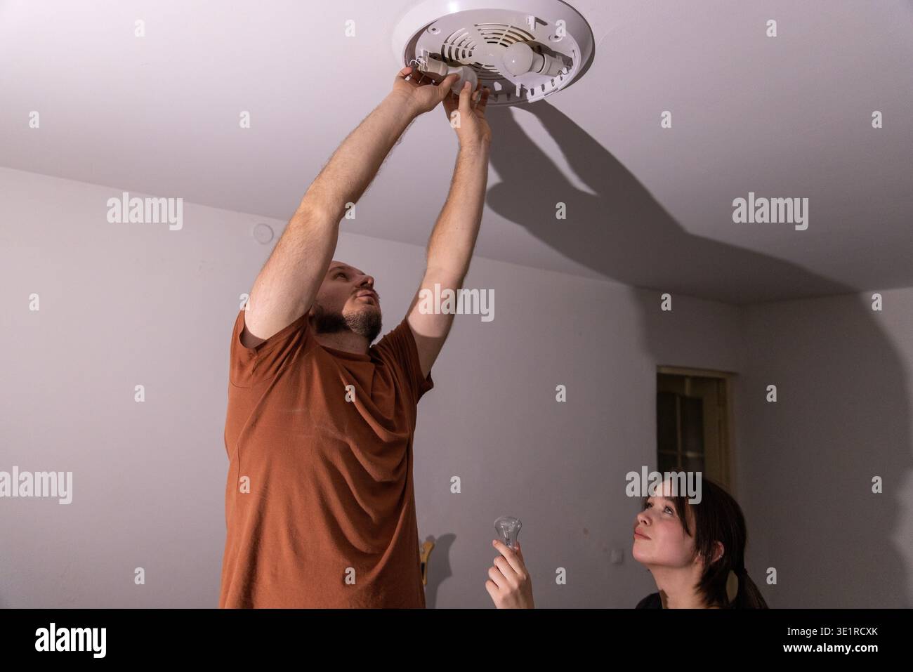 Man installing new light bulbs in ceiling fixture Stock Photo