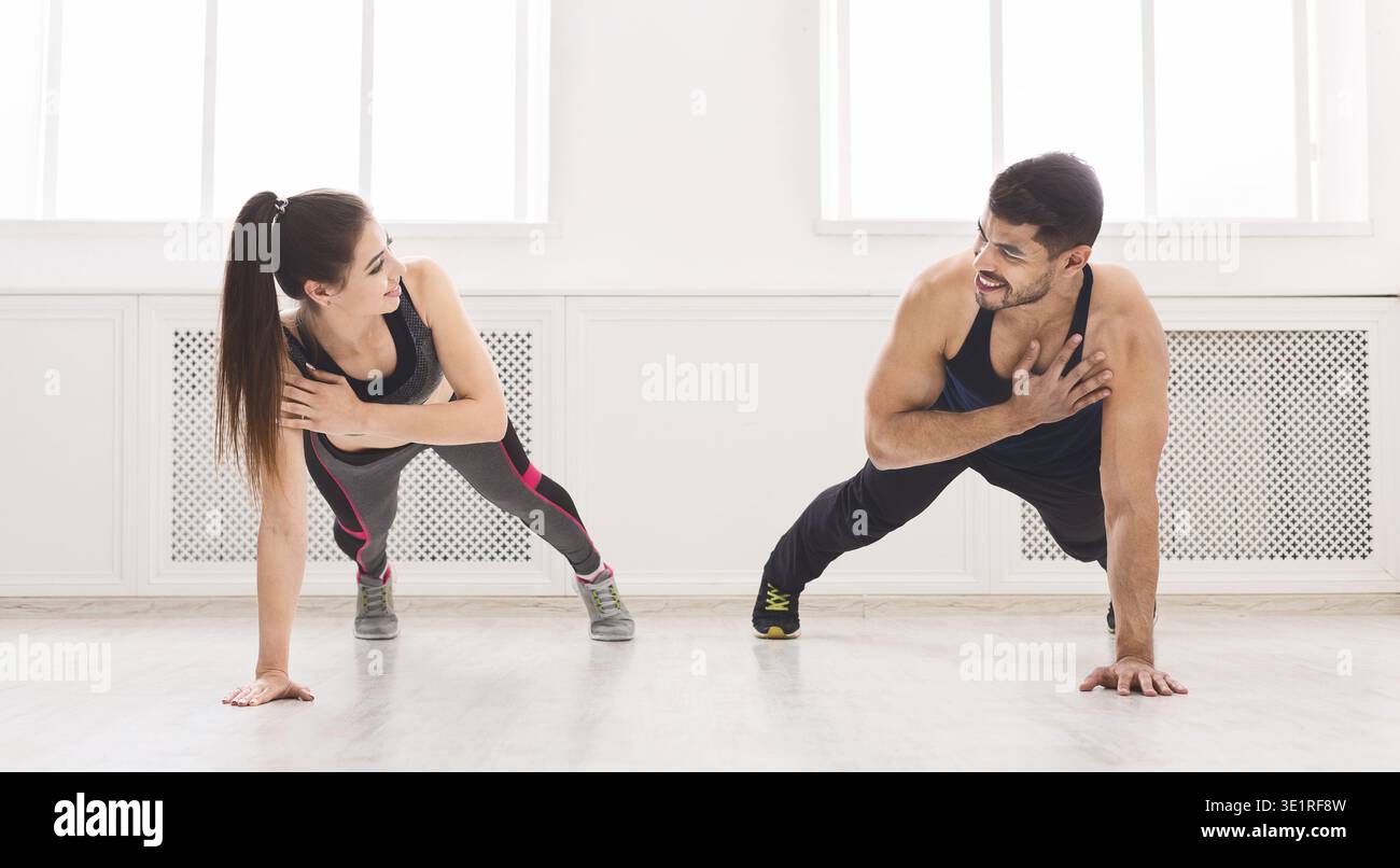 Young fit couple standing in plank with one hand Stock Photo