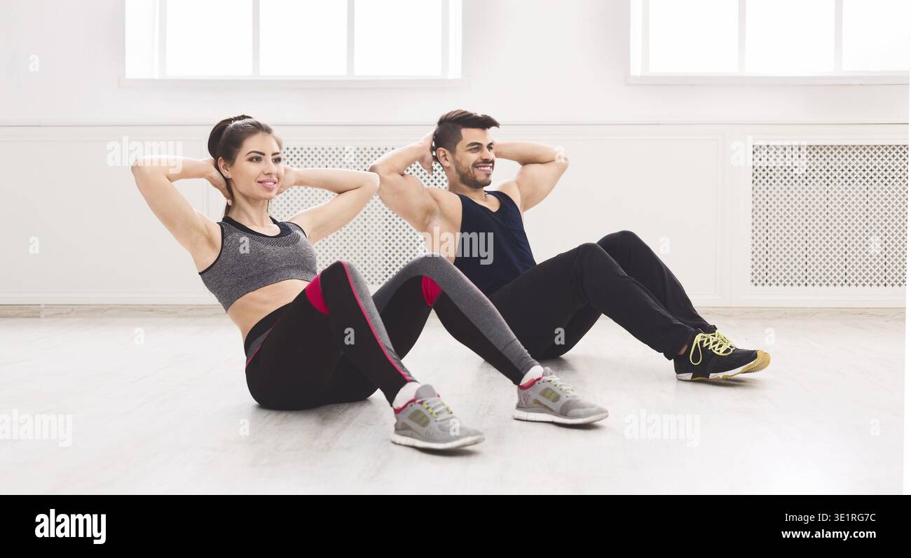 Young couple doing sport exercises on the floor in white studio Stock Photo
