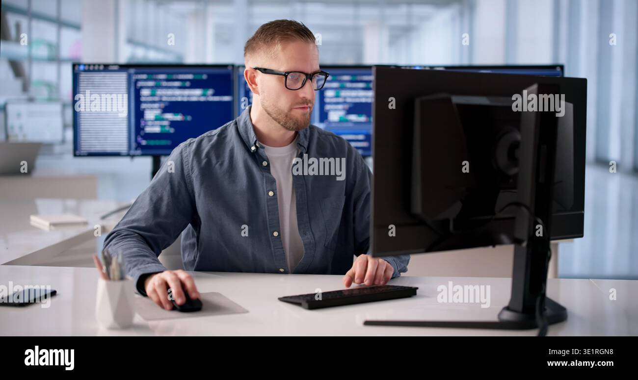 Focused Software Engineer Programming At Desk In Modern Office Stock Photo