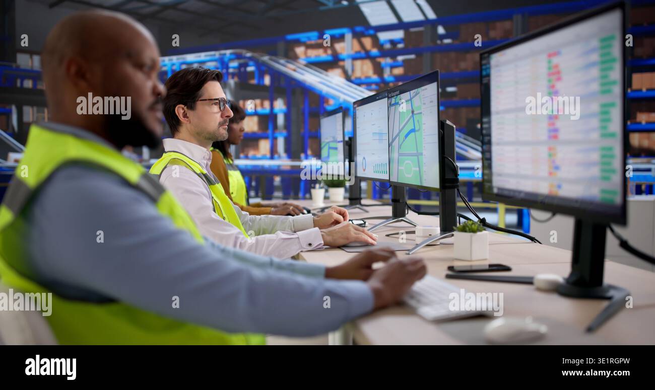 Young Warehouse Worker Uses Computer Software To Track Shipments Efficiently. An Analyst Reviews Inventory Data Stock Photo
