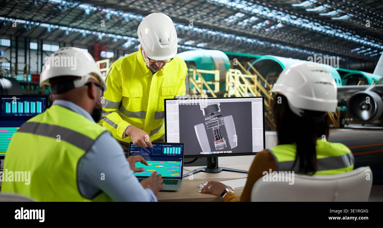 An Engineer And Technician Discuss Jet Engine Repairs Using Laptop Computers. A Diverse Group Stock Photo