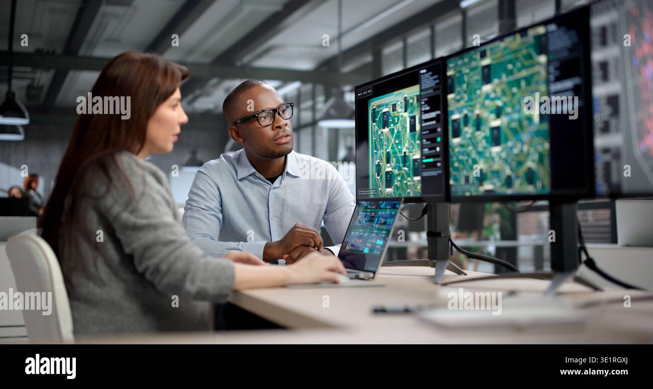 Young Engineer And Developer Collaborate On Electronic PCB Design At Office. Two Managers Coaching Team Stock Photo