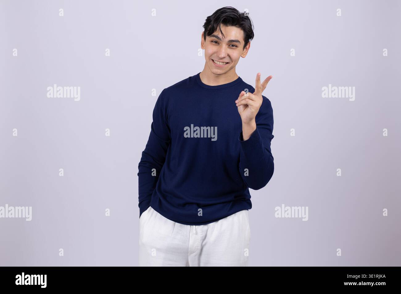 Young man showing victory sign with fingers posing Stock Photo