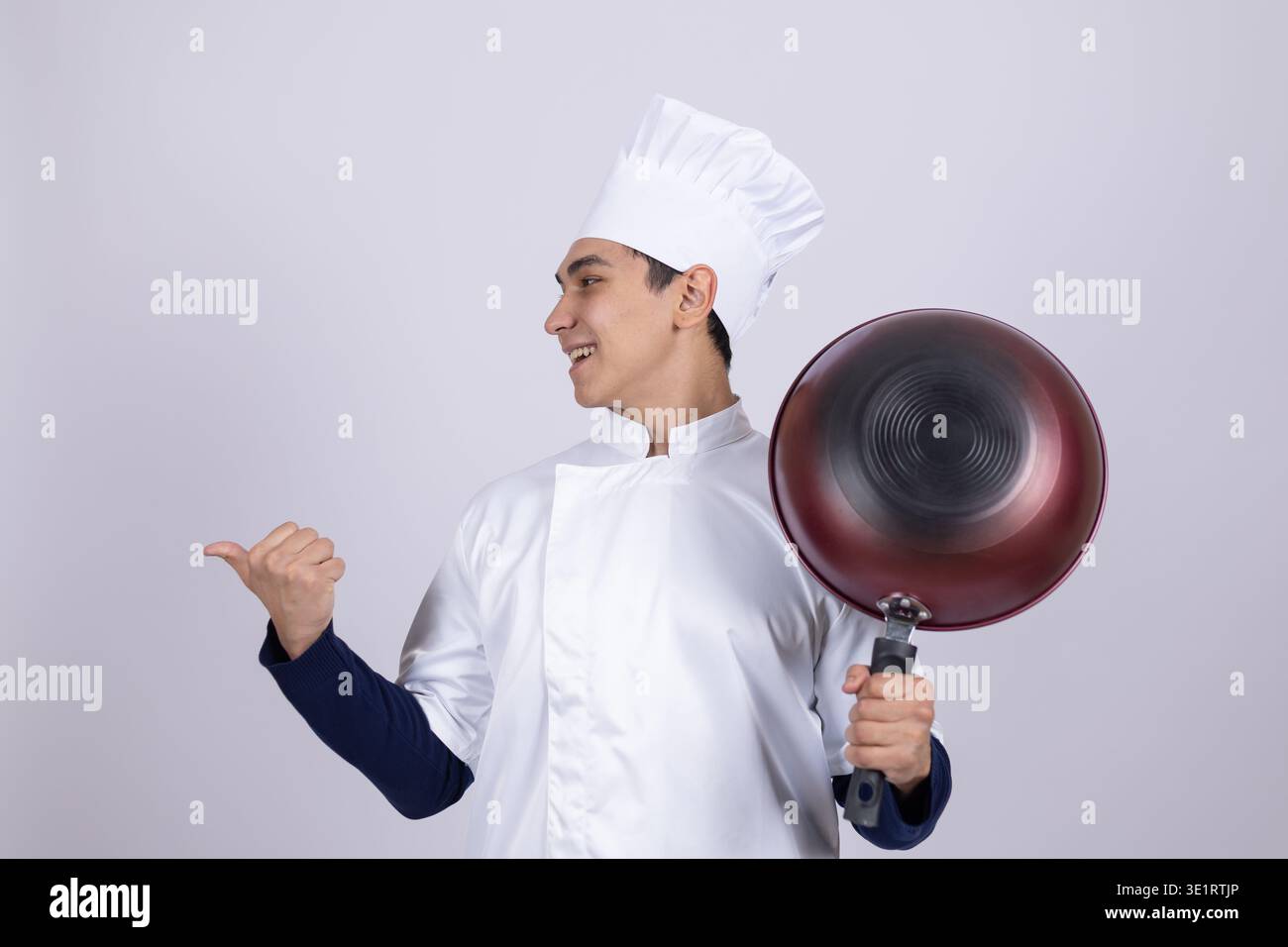 Chef in white uniform holding a pan and gesturing Stock Photo