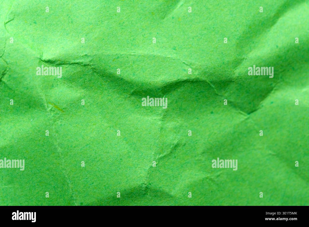 Crumpled green paper showcases unique textures and vibrant hues, creating art. Stock Photo