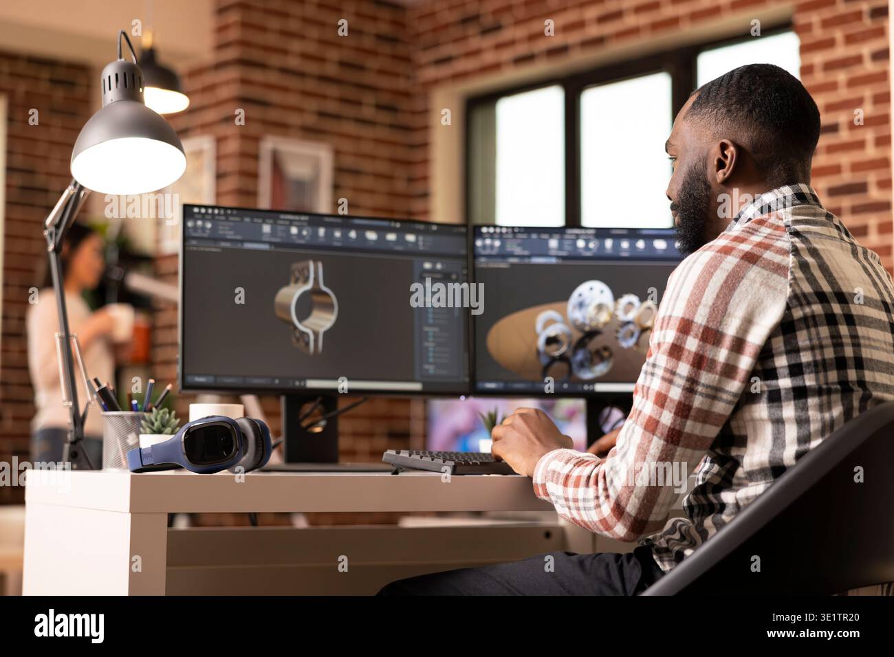 Creative male developer using dual monitors, reviewing gears and ...
