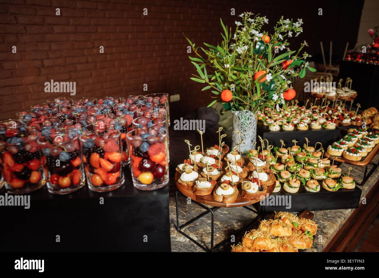 Stylish buffet setup featuring fruit cups, canapes, and floral ...