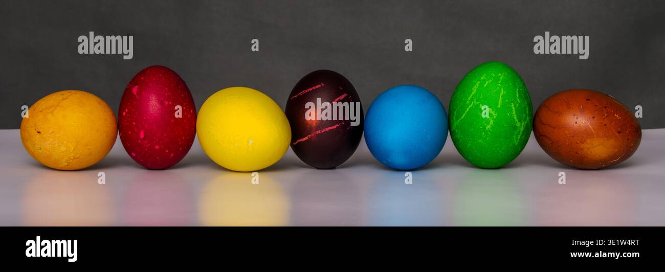 Easter eggs painted in different colors with custom patterns, lined up in a row on a gradient background, a symbol of the holiday, front view Stock Photo