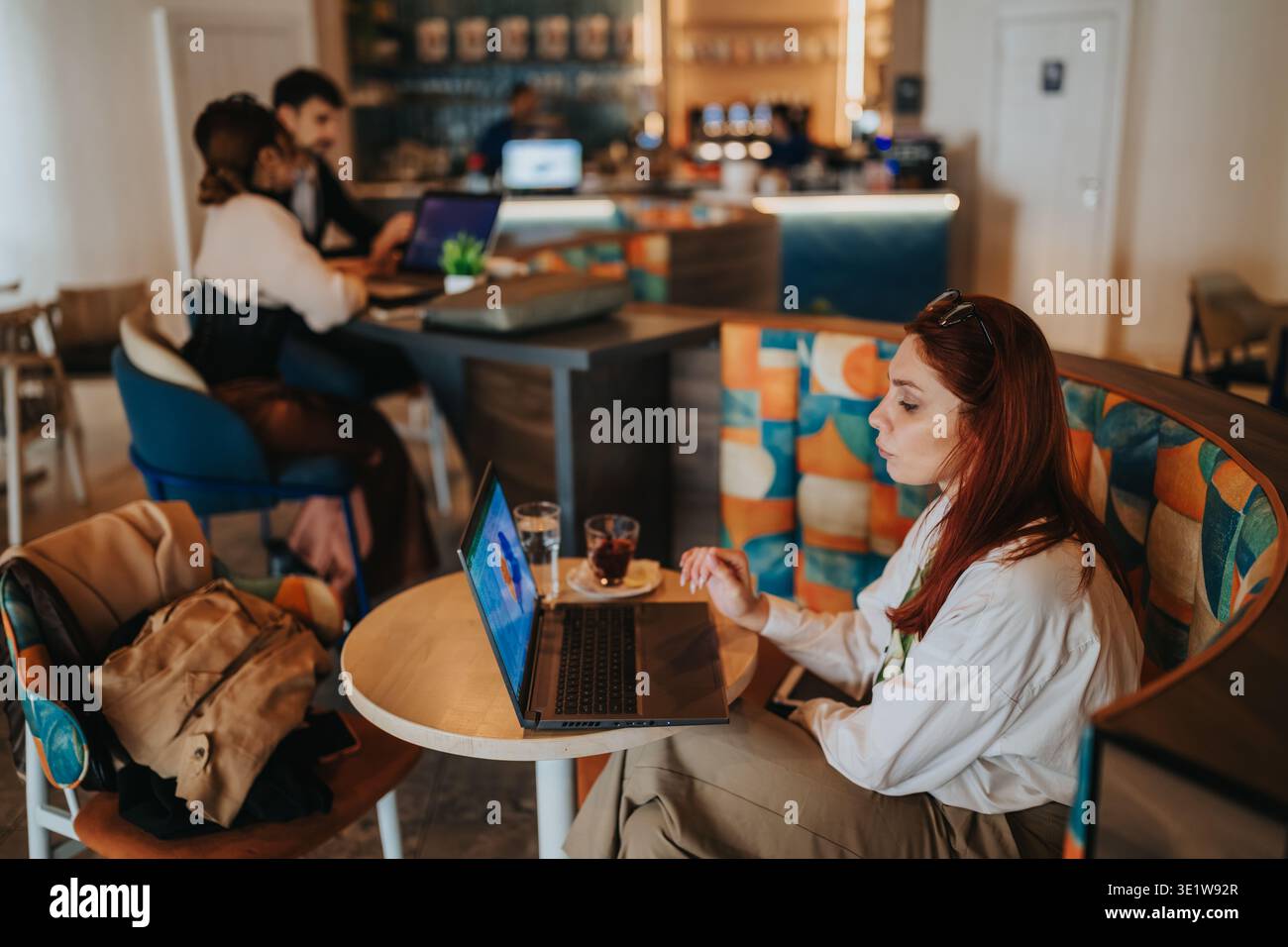 Business workers in a cafe working on laptops and drinking coffee during a remote meeting Stock Photo