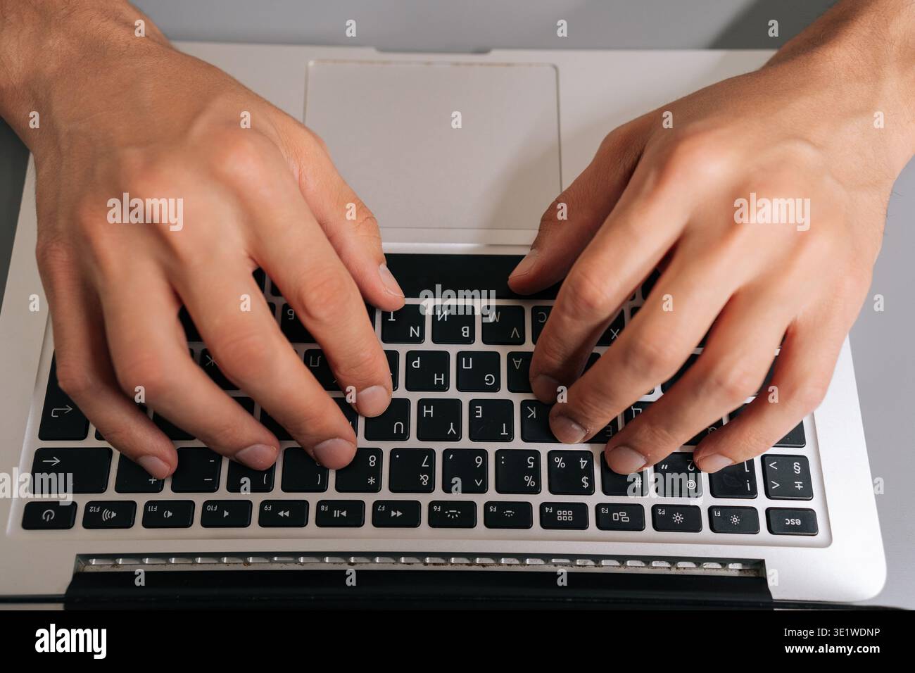 High-angle view of unrecognizable freelancer male typing on laptop keyboard, professional home office scene showing remote work, coding, online Stock Photo