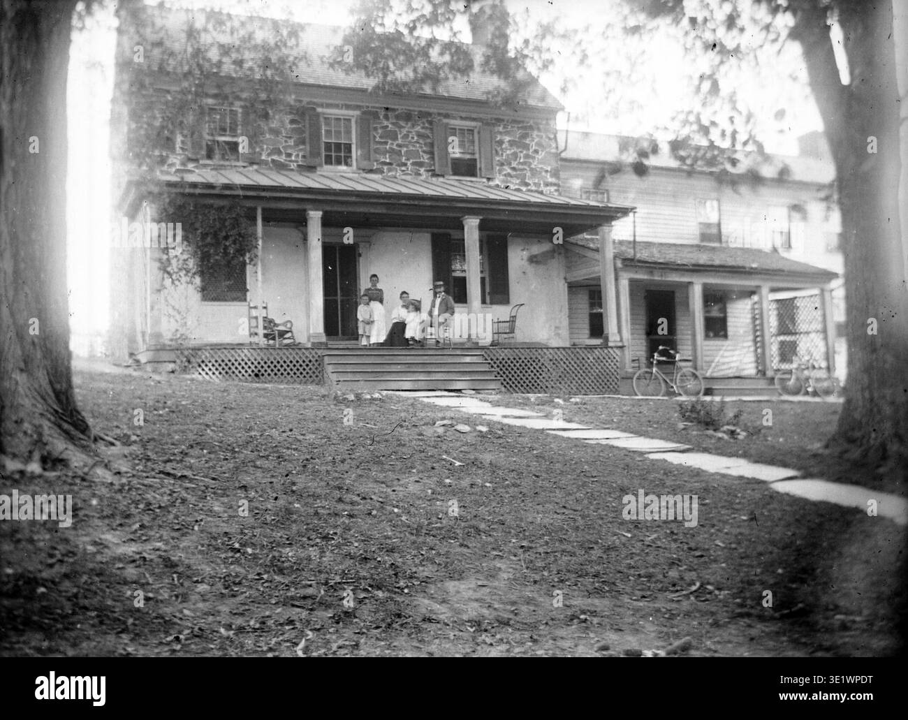 Amos, Elizabeth, and Hannah Slaymaker sit on the porch of the 