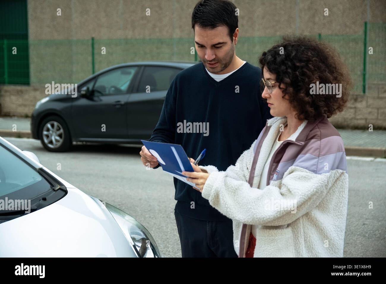 Driving instructor teaching student how to fill out documents Stock Photo