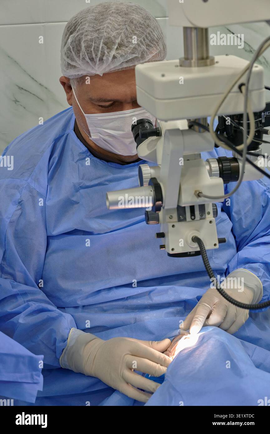 Loop Microscope Surgery Concentrated male ophthalmologist performing microsurgery using a ...
