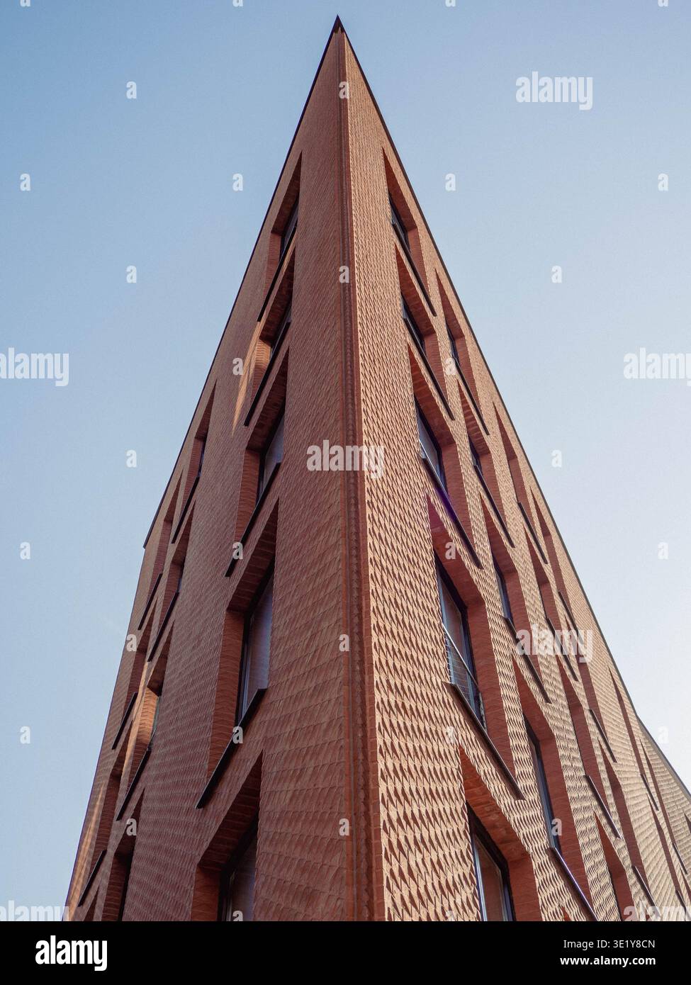Modern red brick building with textured facade and angular corner rising against clear sky in Rottermani district, Tallinn Stock Photo