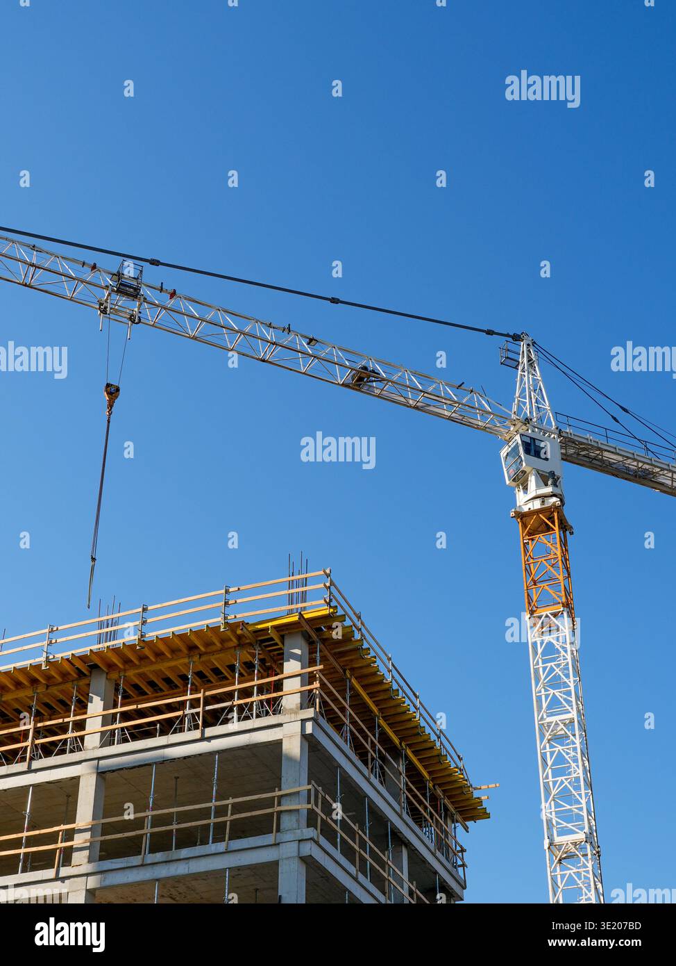 Tower crane working above a concrete building under construction with ...