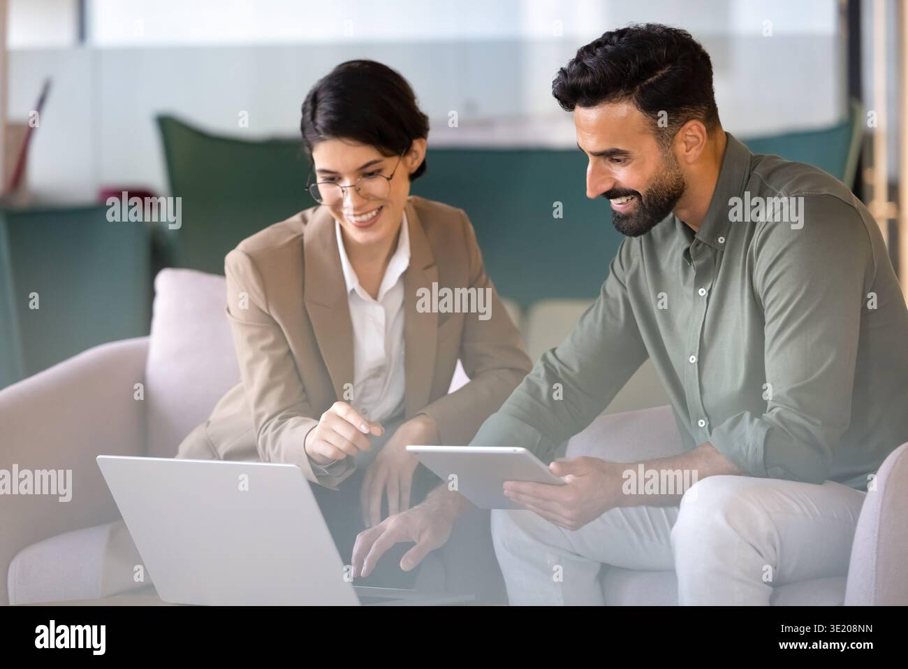 Team members collaborating, analyzing business data using laptop and tablet Stock Photo
