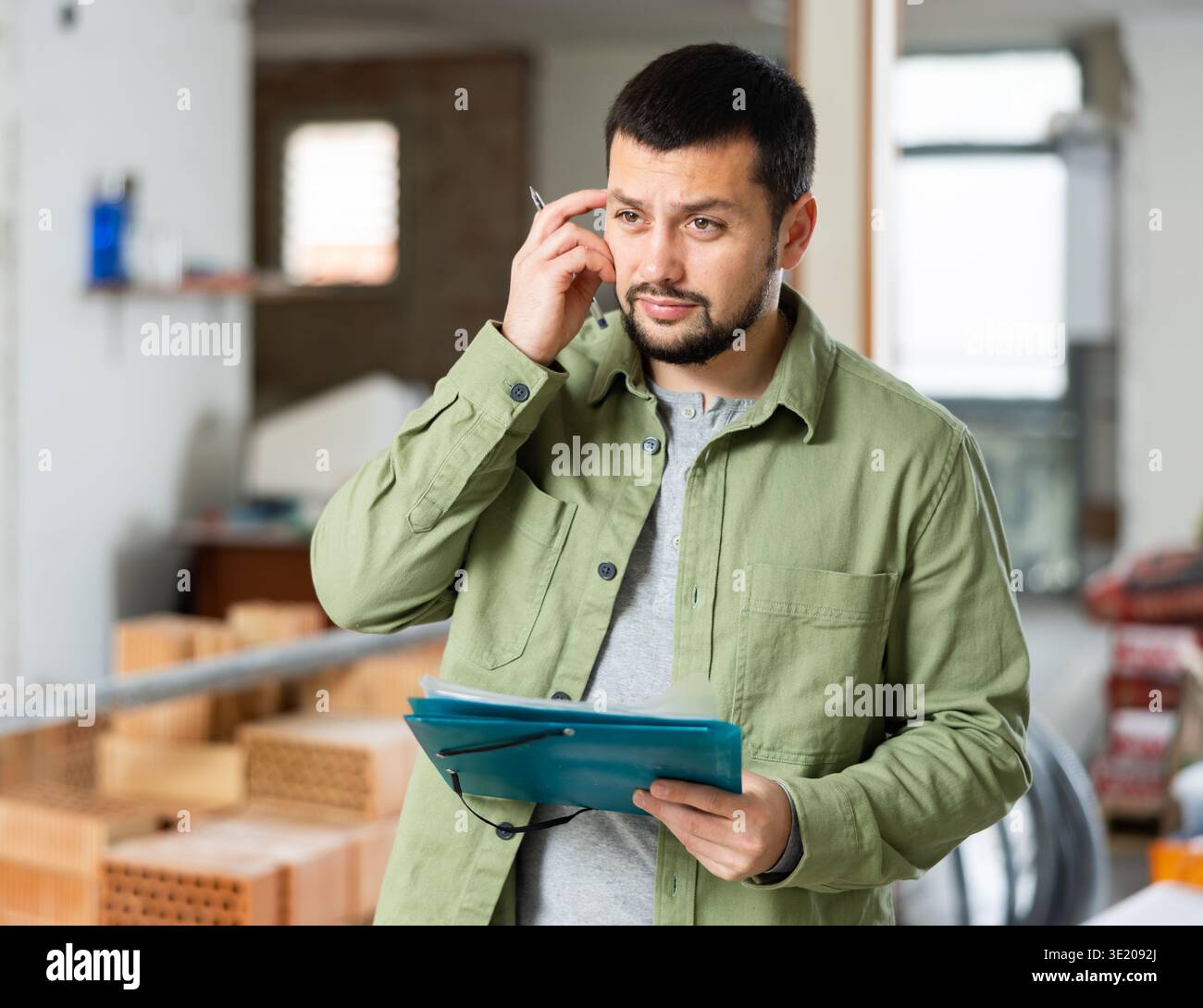Architect making notes on indoor construction site Stock Photo