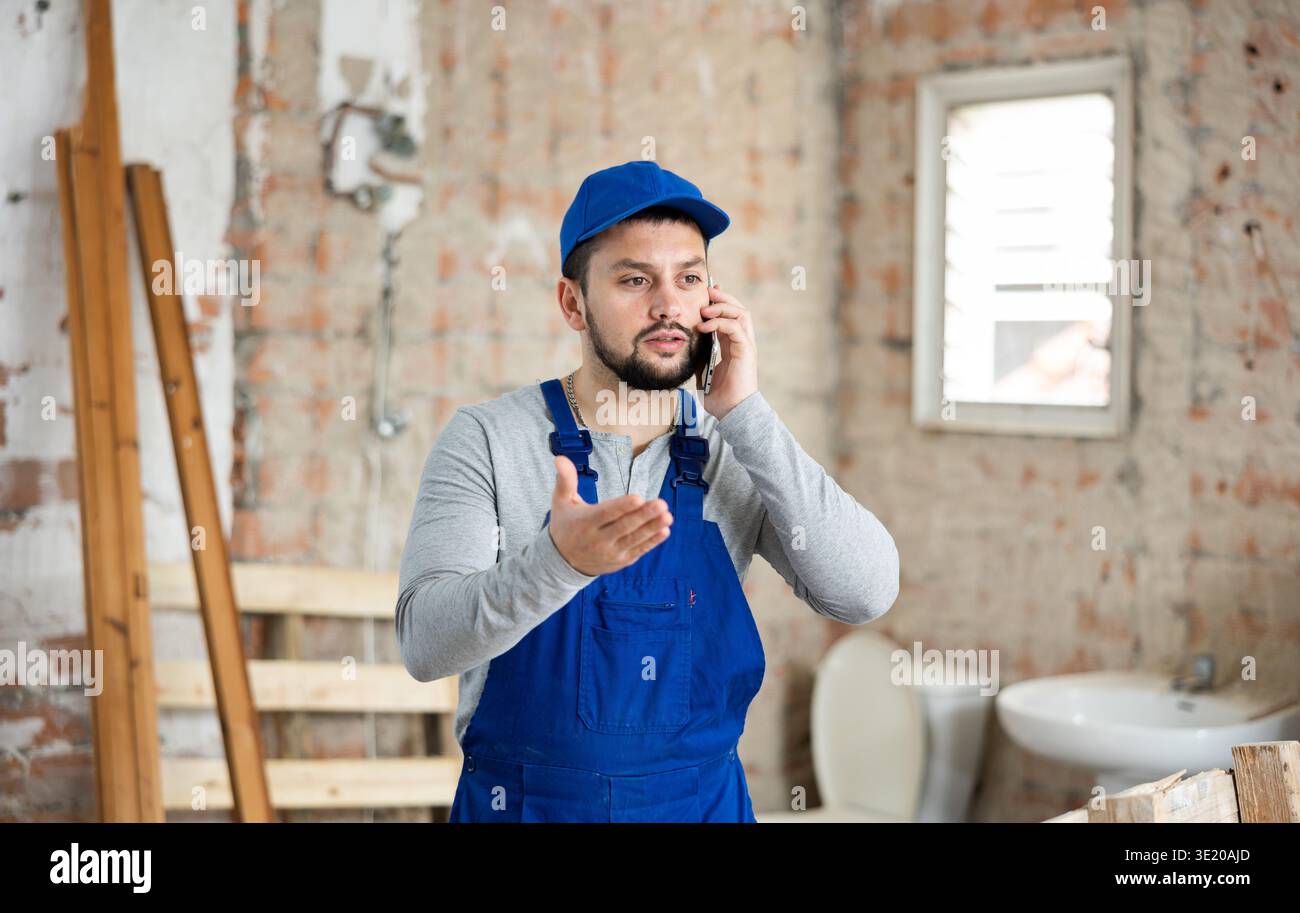 Young builder talking on phone in building under renovation Stock Photo