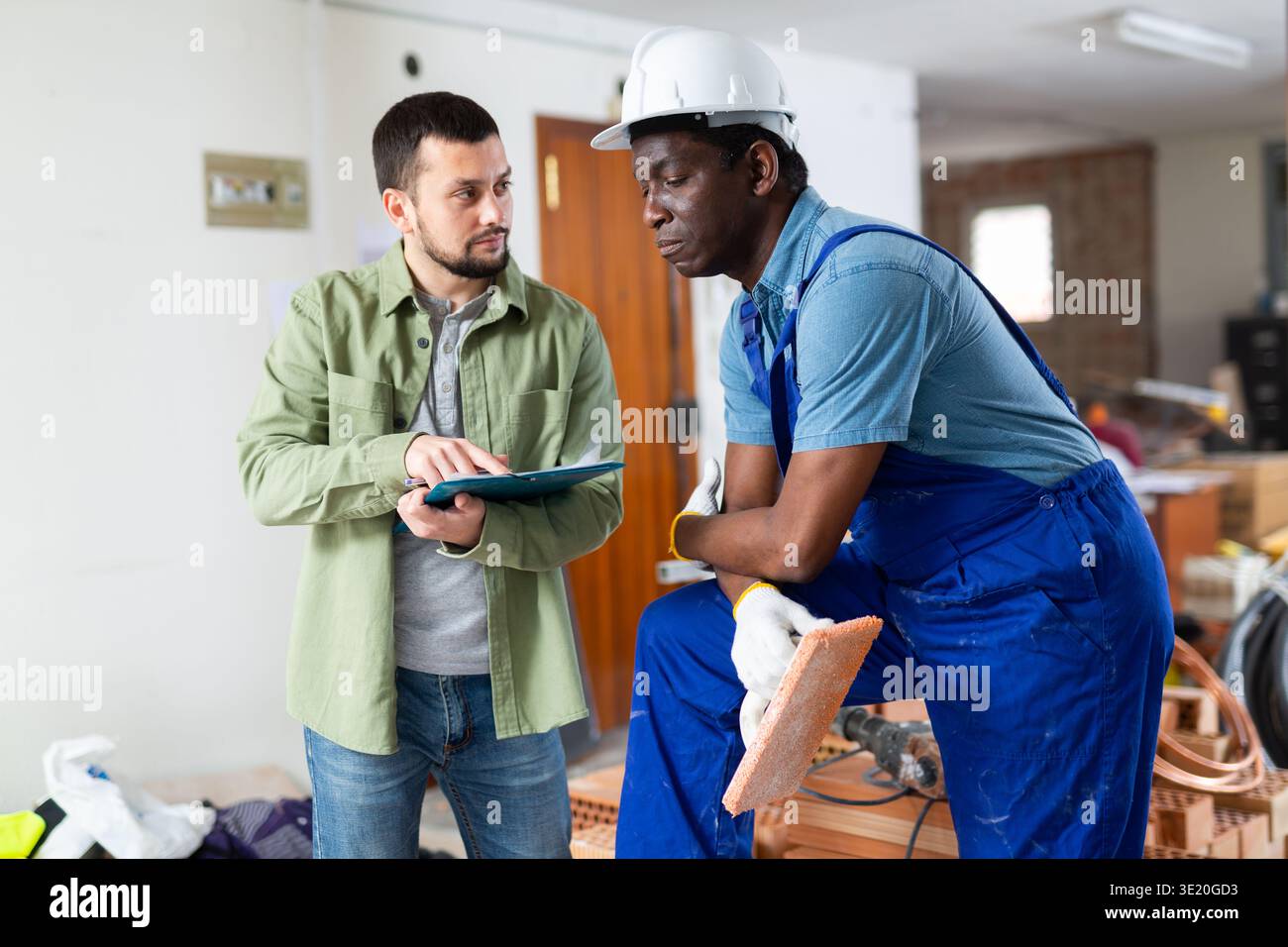 Engineer shows the estimate to a builder, explaining the working moments Stock Photo