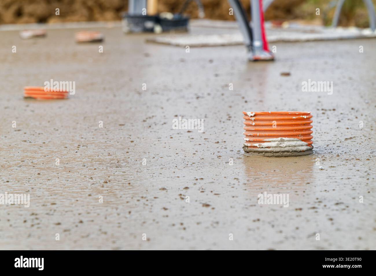 Concrete slab under construction with orange drainage pipes embedded in ...