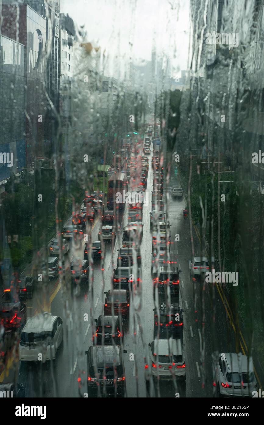 Rain streaks glass, blurring wet city streets. Vehicles move slowly ...