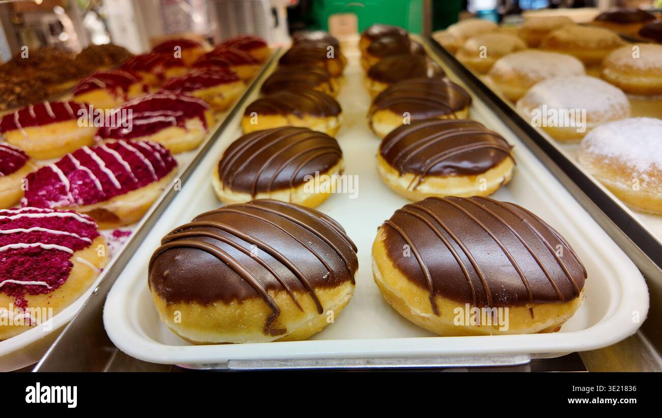 Donuts with chocolate icing and pink toppings on display Stock Photo