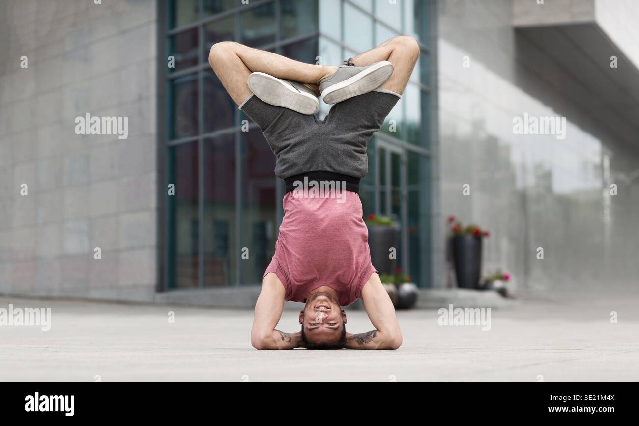 Professional yoga man doing headstand exercise outdoors Stock Photo