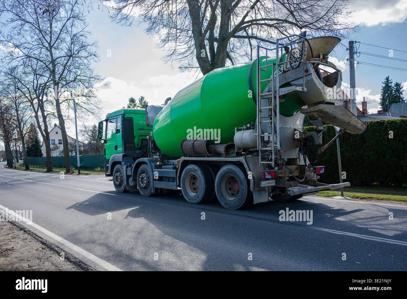 A green concrete mixer truck is driving through the city Stock Photo