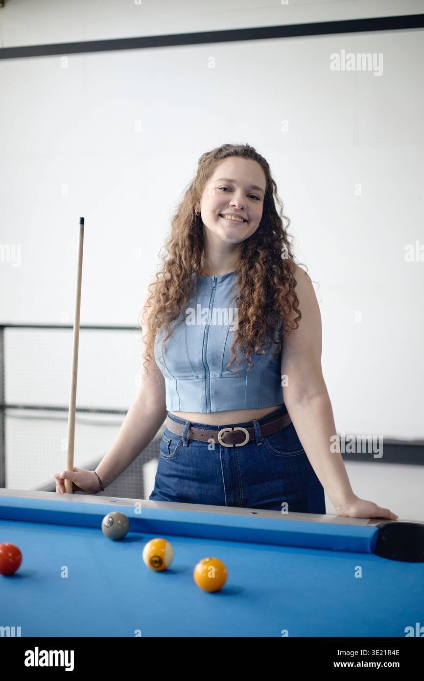 Vertical of Portrait of Young Adult Woman Smiling While Playing Billiards Stock Photo