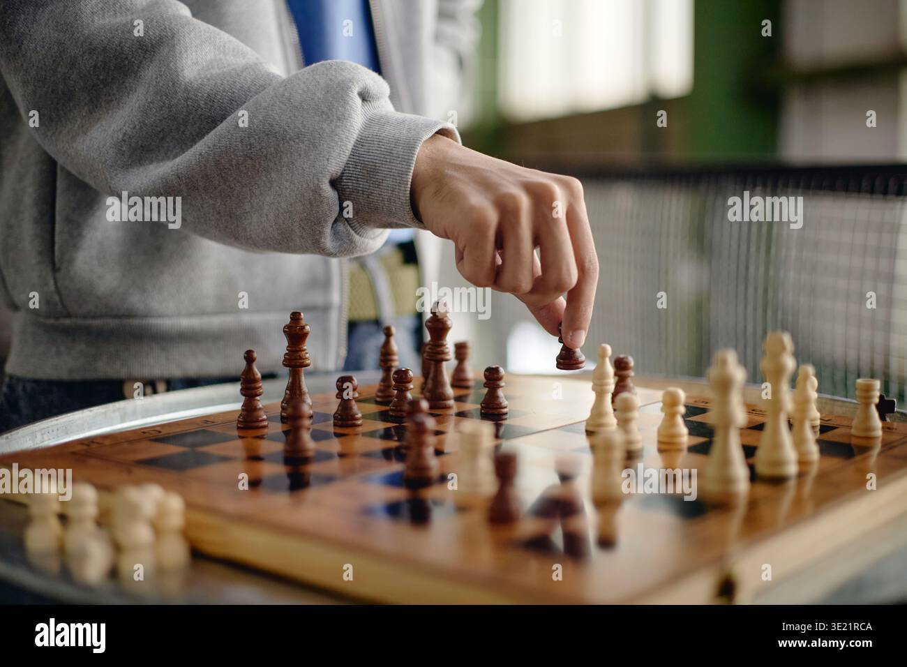 Young Adult Man Strategizing Move While Playing Chess Indoors Stock Photo