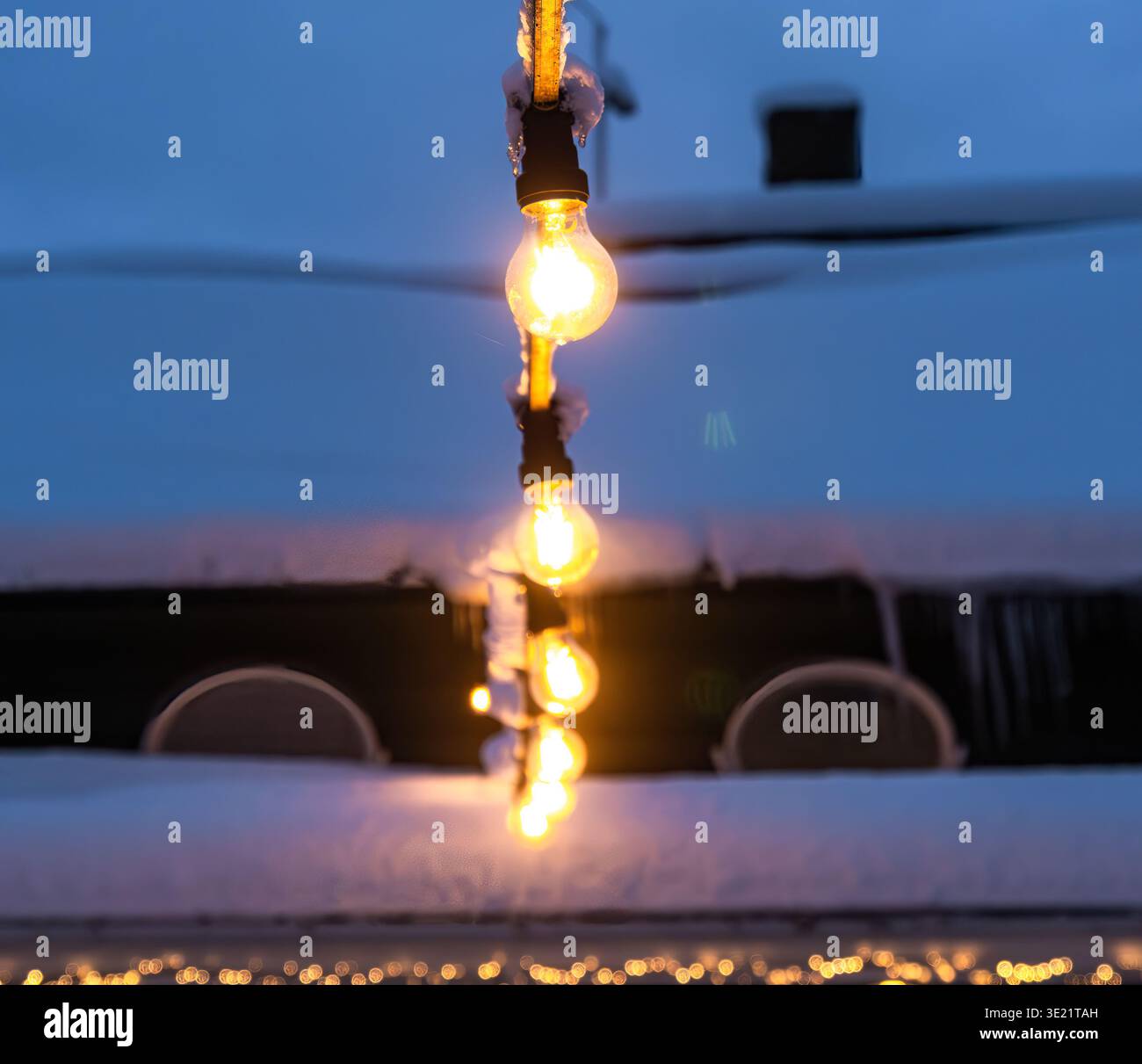 String lights glowing warmly in a snowy winter setting. Stock Photo