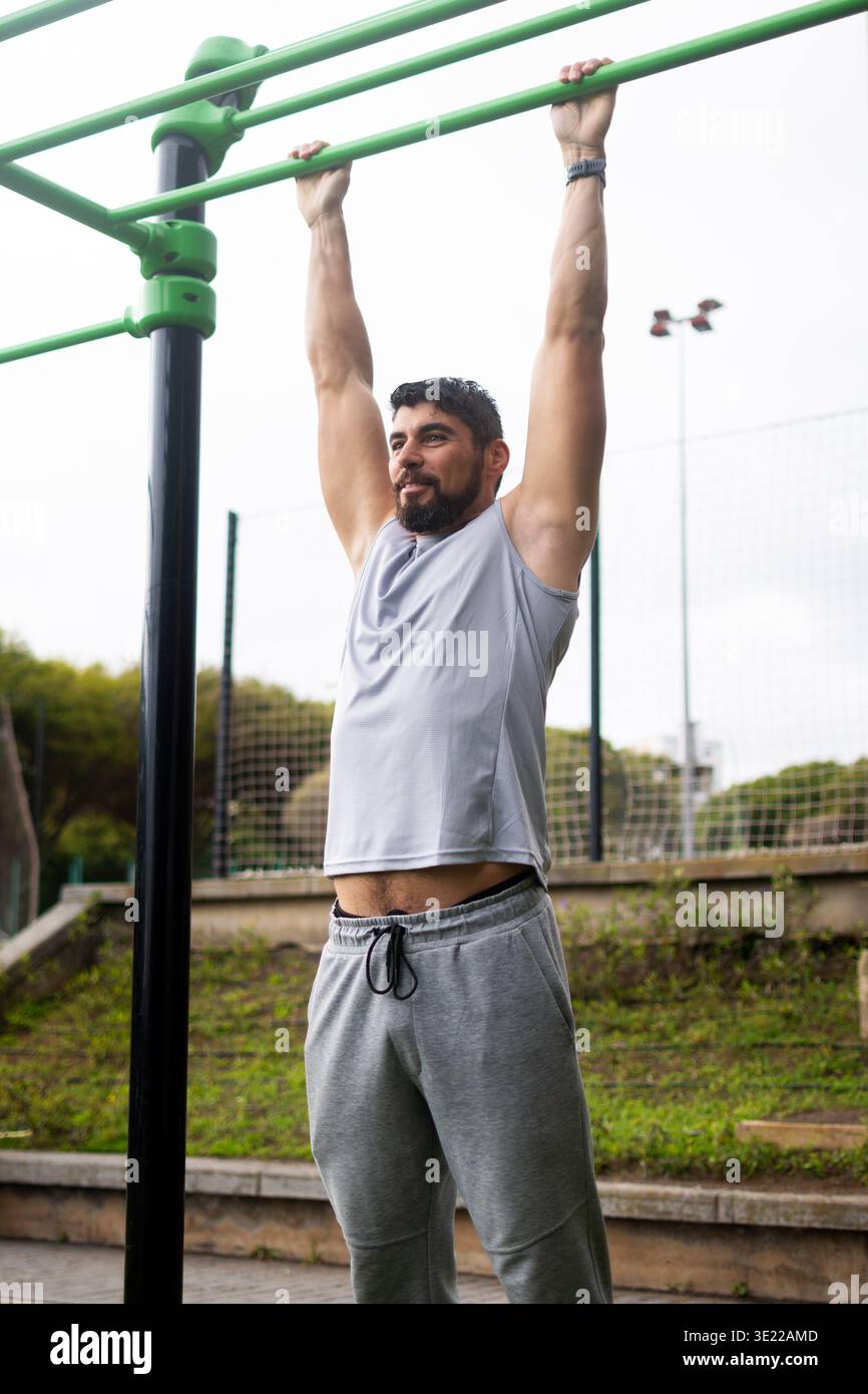Young man doing pull-ups on bar in outdoor park workout Stock Photo