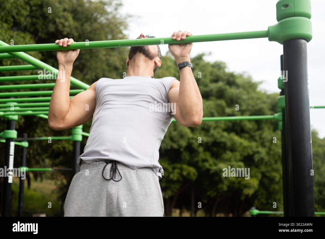 Young man doing pull-ups on bar in outdoor park workout Stock Photo