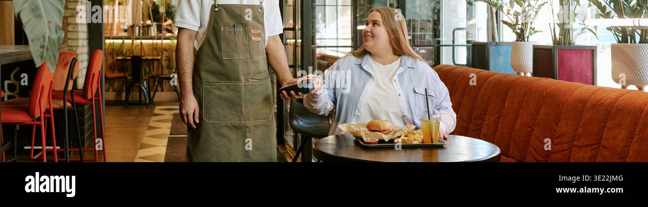 Young Woman Paying Restaurant Bill Using Contactless Card Reader Stock Photo