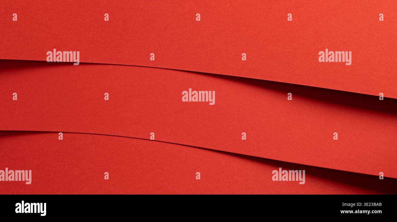 Horizontal red paper bands create a bold layered background with graphic rhythm. Smooth matte strips overlap with subtle depth and shadow forming a cl Stock Photo