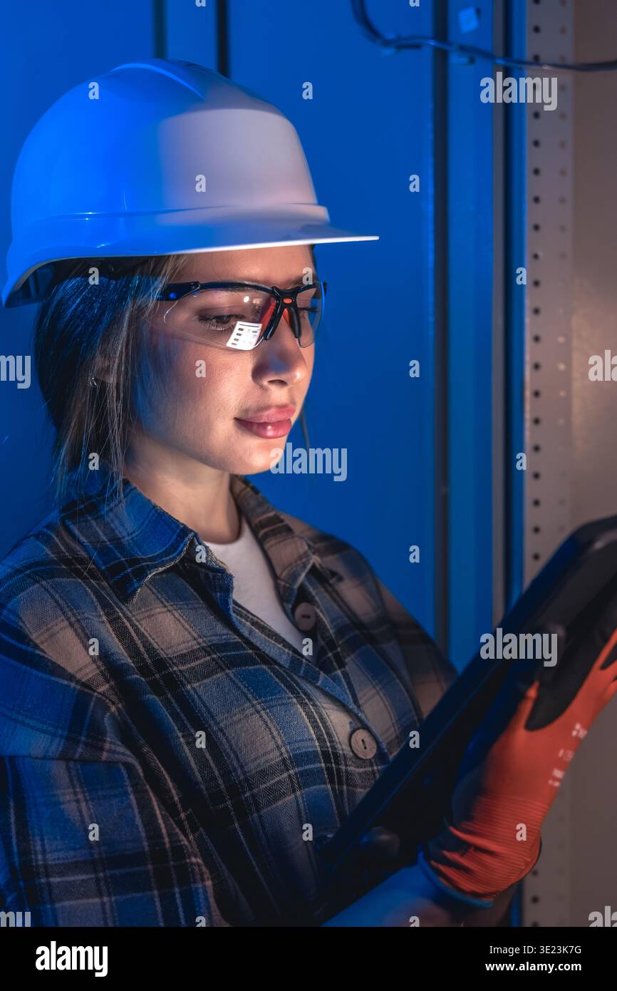 Electrician inspecting electrical switchboard using tablet device. Technical system control. Stock Photo