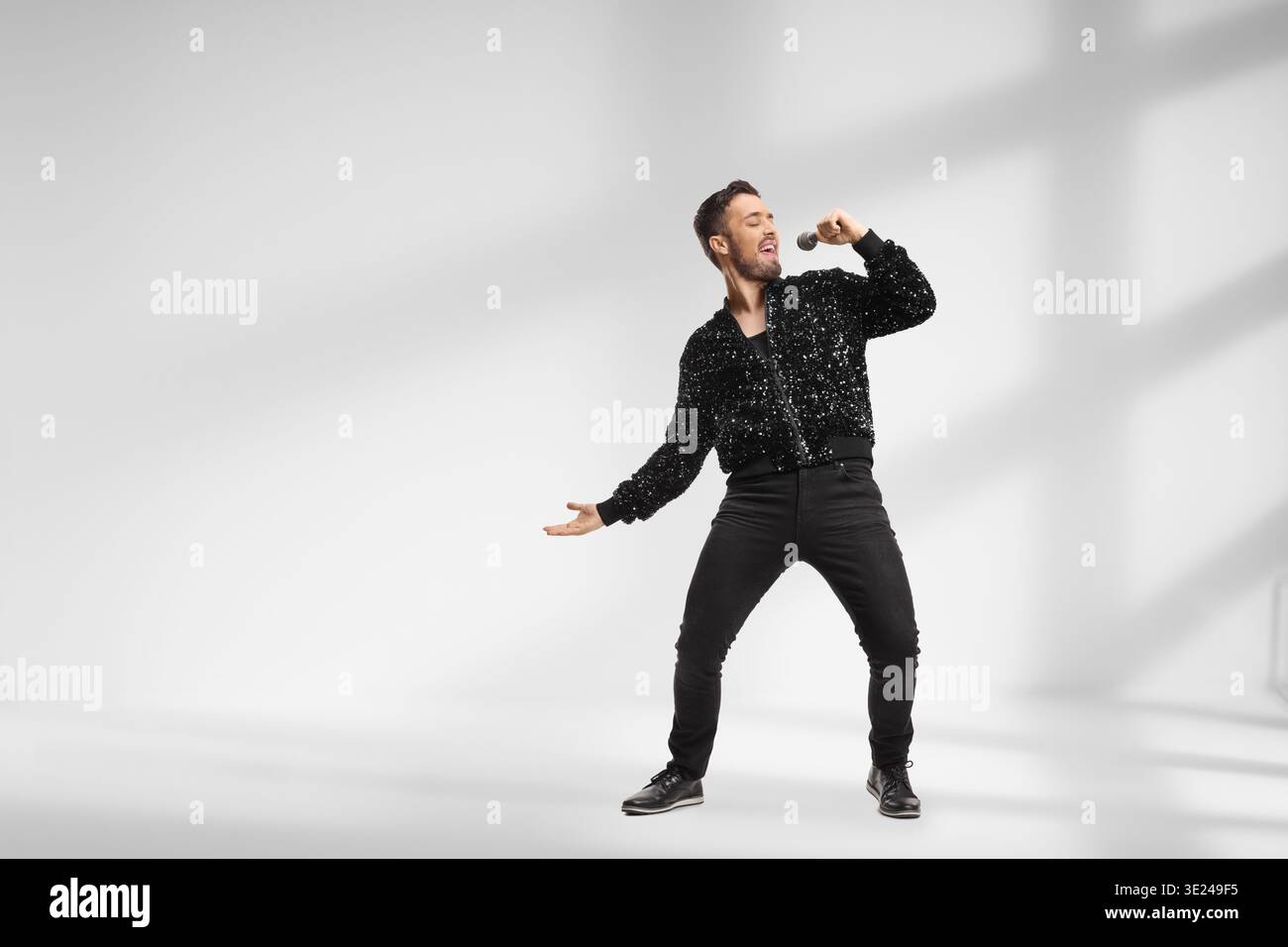 Male singer in a black sequin bomber jacket in a studio Stock Photo