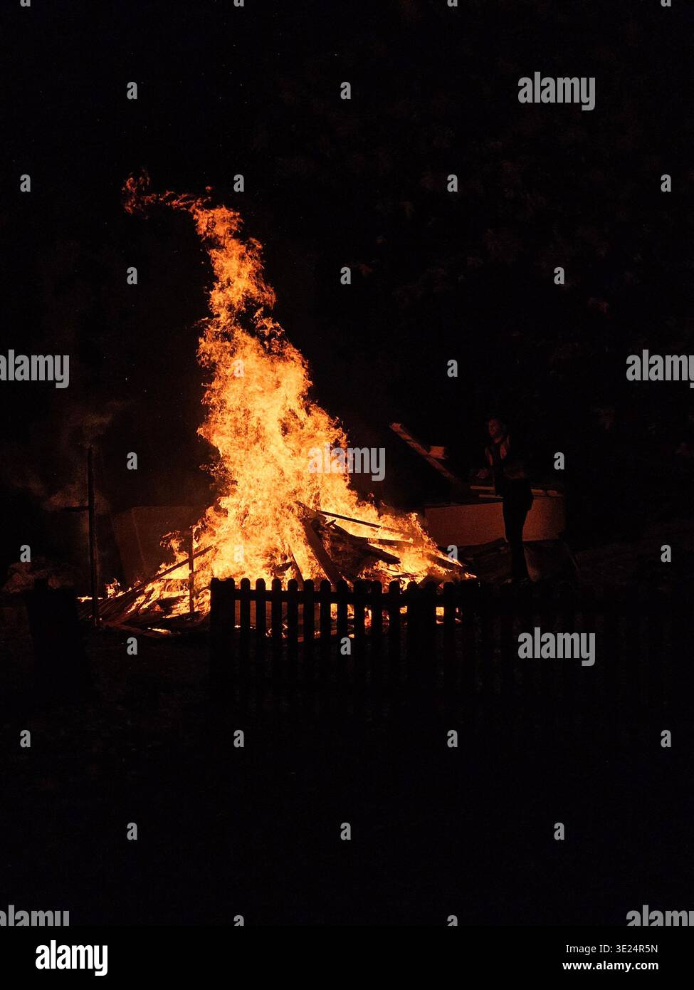 A blazing bonfire lights up the night sky on Bonfire Night, surrounded by glowing embers and capturing the warmth and festive spirit of the celebratio - Smartphone Captured Stock Image