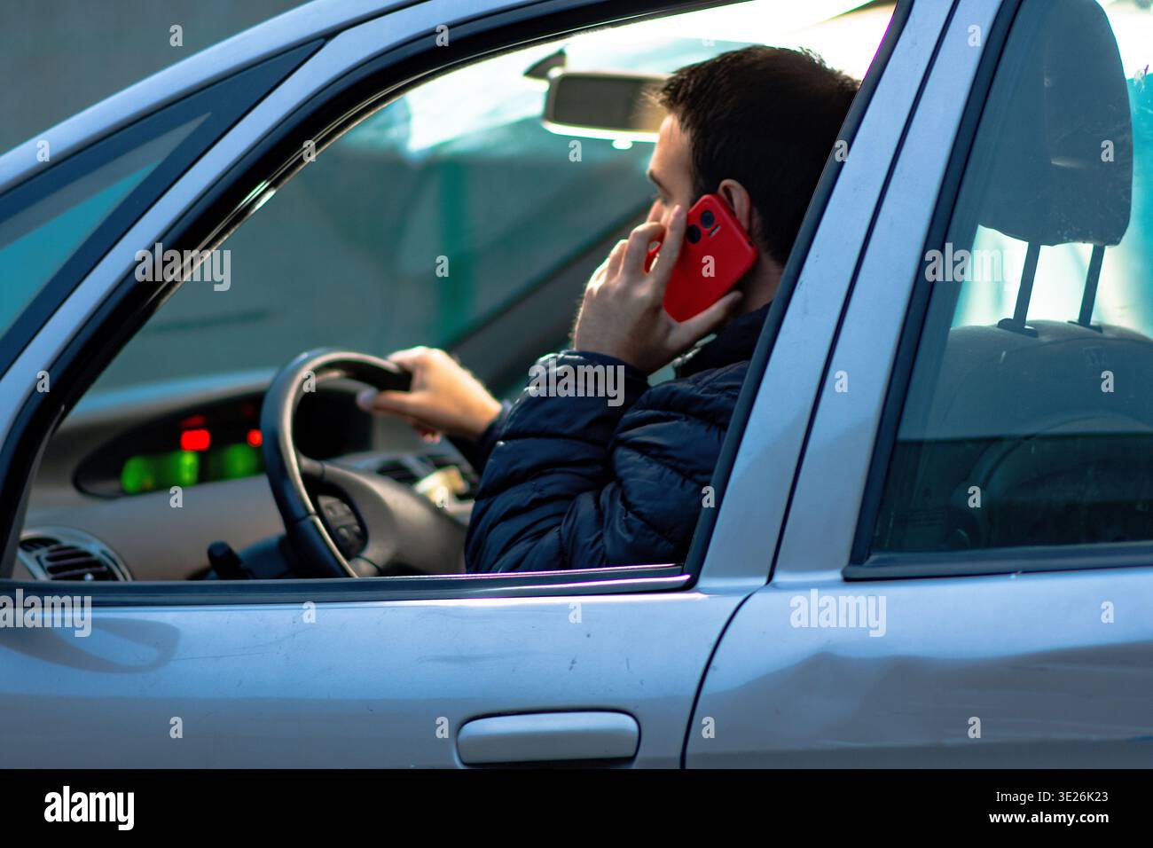 Driver distracted using mobile phone while operating vehicle Stock Photo