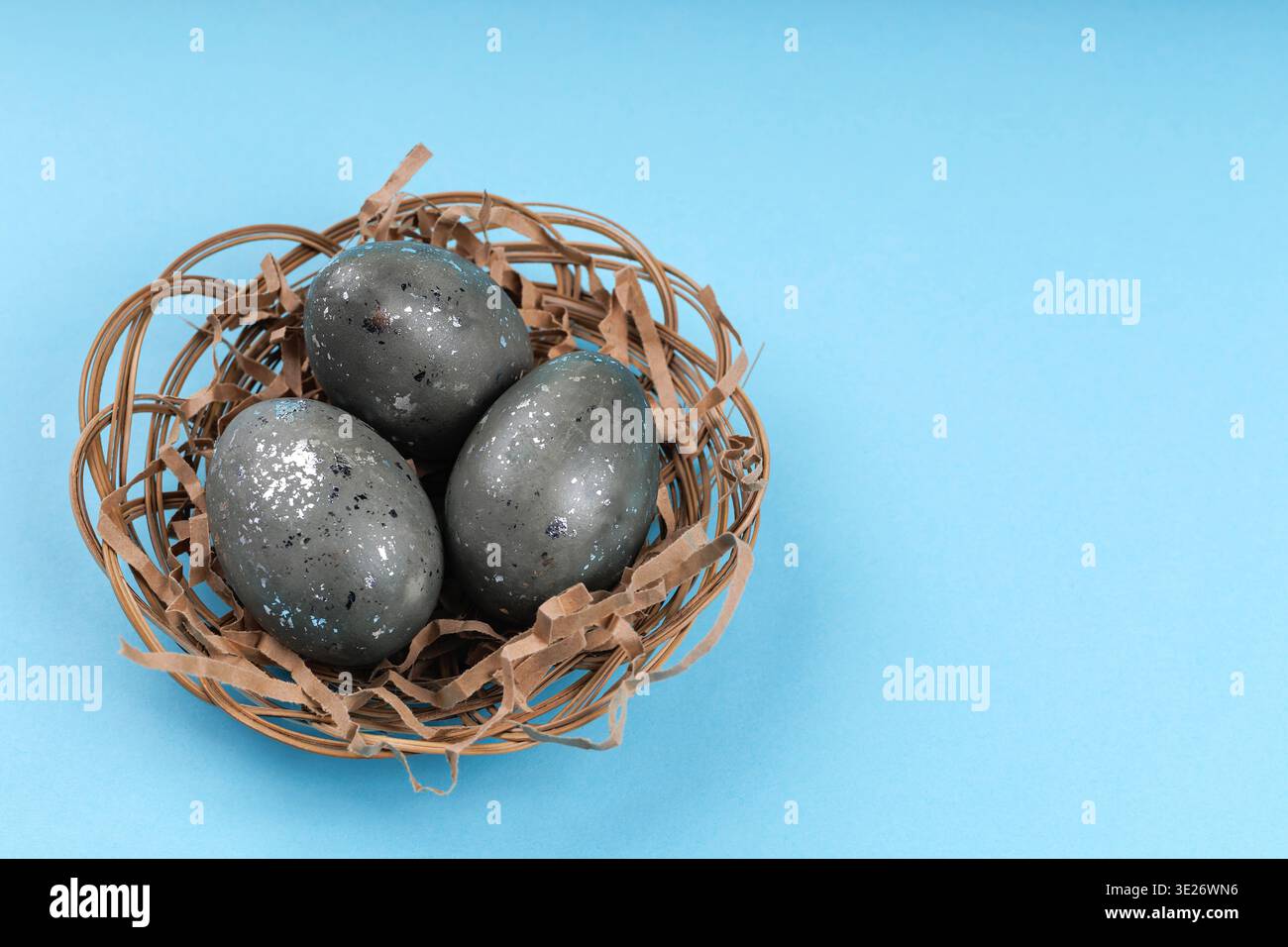 Decorative Easter eggs with silver texture in nest on blue background Stock Photo
