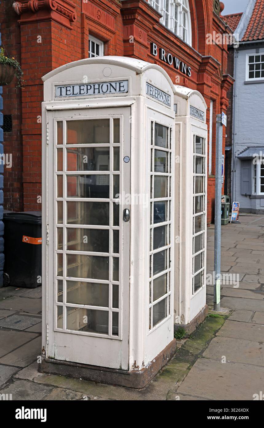 White KCOM telephone kiosk in Beverley town centre, East Riding of Yorkshire, England, beside historic brick-fronted buildings. Stock Photo