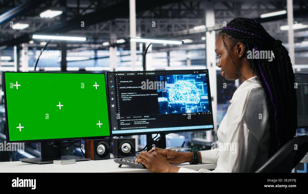 Data center engineers managing AI systems for uptime and efficiency using chroma key PC. Teamworking IT specialists using artificial intelligence on green screen computer in server hub, camera A Stock Photo