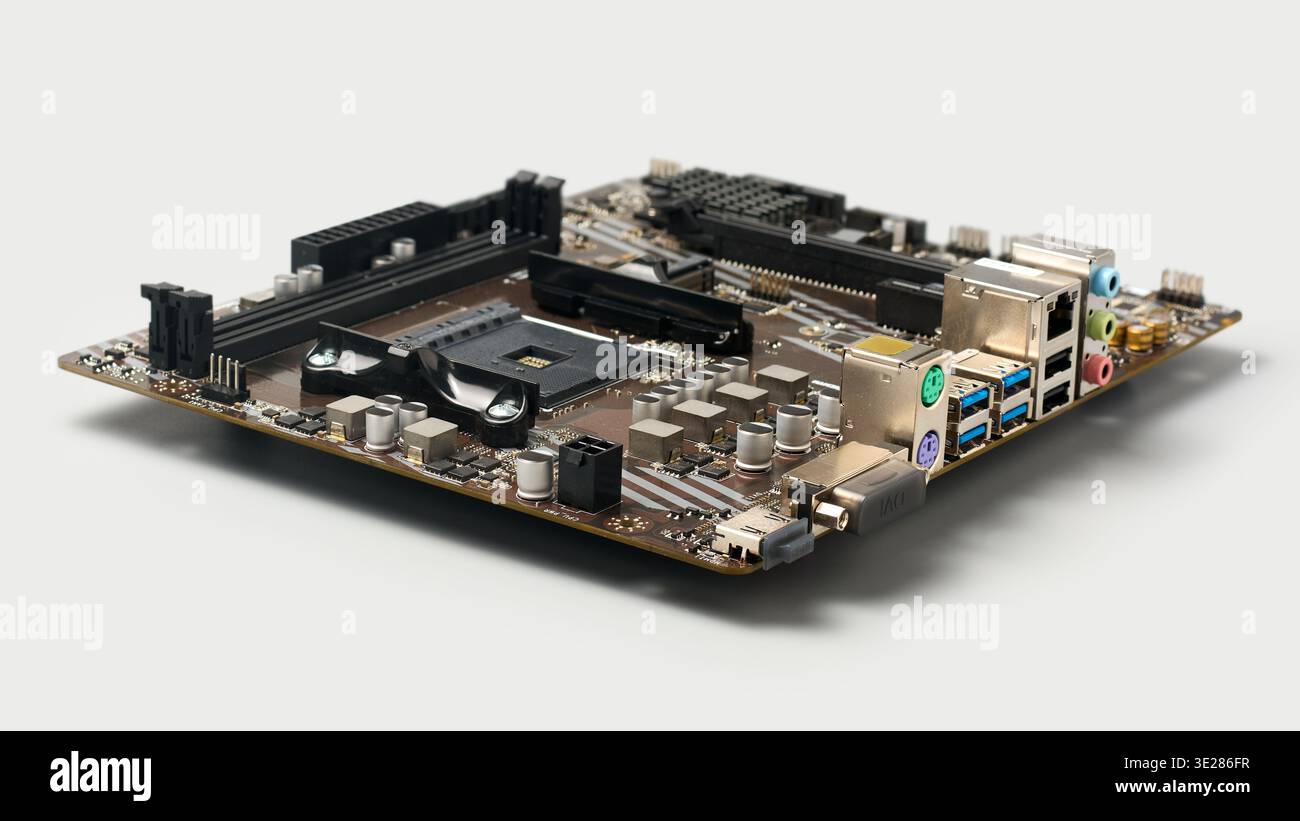 desktop computer motherboard isolated light gray background, empty cpu socket and memory slots with electronic components, angle view with soft focus Stock Photo