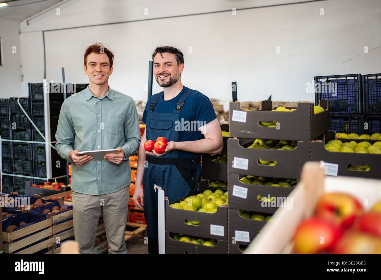 Produce workers discussing apples in fruit warehouse Stock Photo