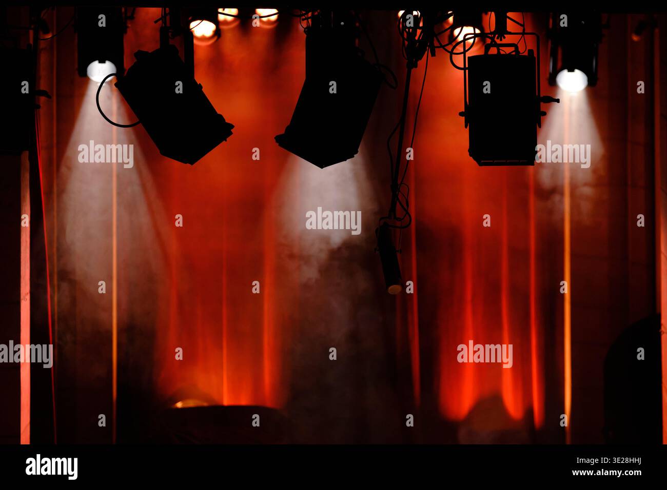 Professional Stage Spotlights and Beams of Light with Red Glow in a Dark Theater Stock Photo