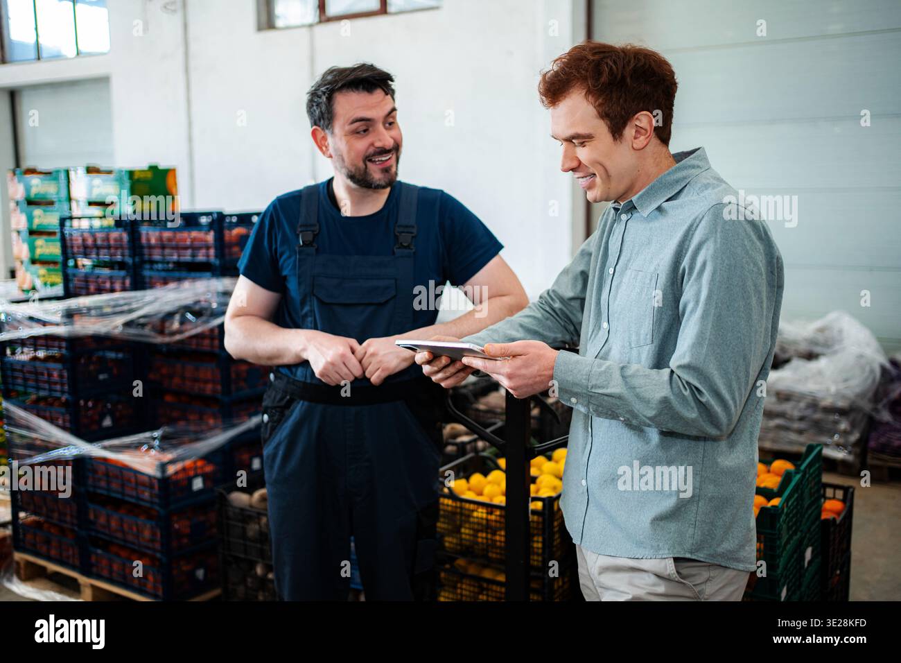 Workers discussing logistics in fresh produce warehouse with tablet Stock Photo
