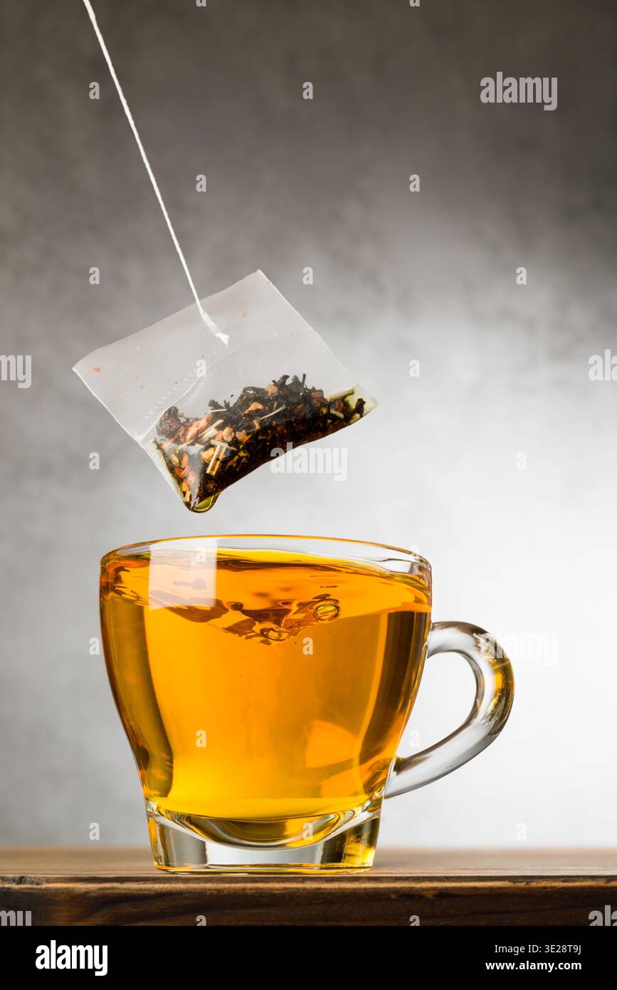 Glass cup of tea on wooden table with tea bag. Stock Photo